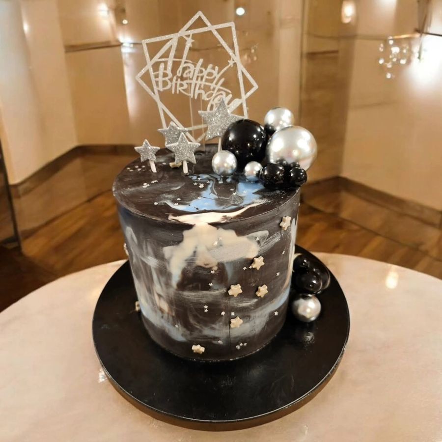 Black and silver marbled birthday cake with stars and spheres