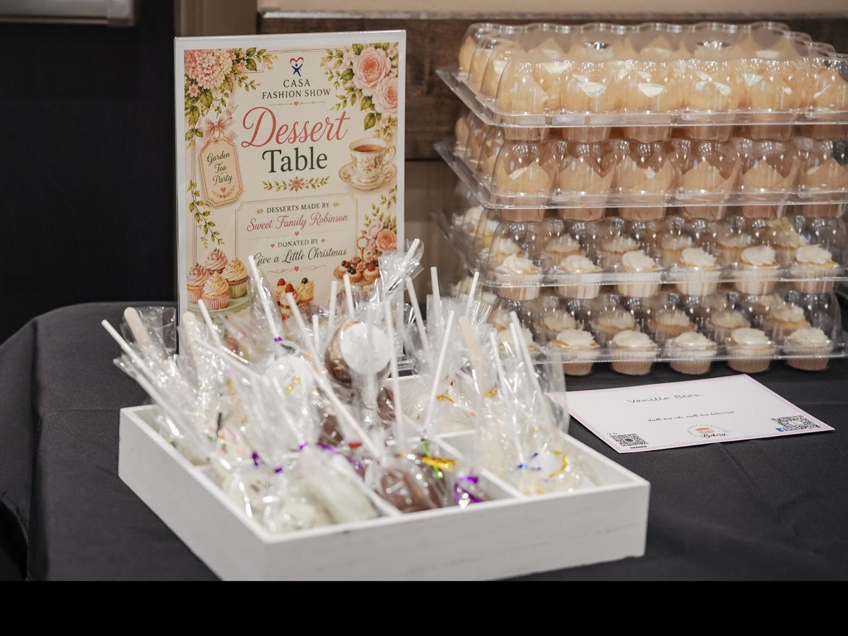 Dessert table at the CASA Fashion Show with wrapped cake pops and trays of cupcakes
