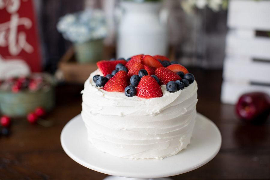 White buttercream cake topped with fresh strawberries and blueberries