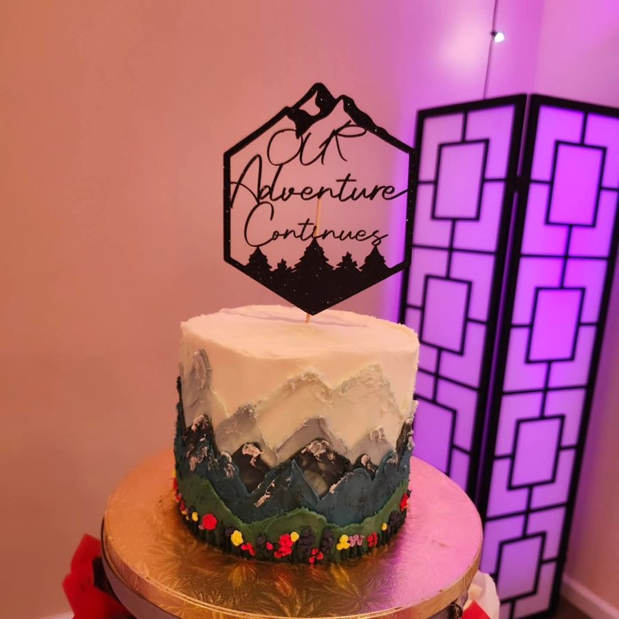Painted buttercream mountain cake with an Our Adventure Continues topper