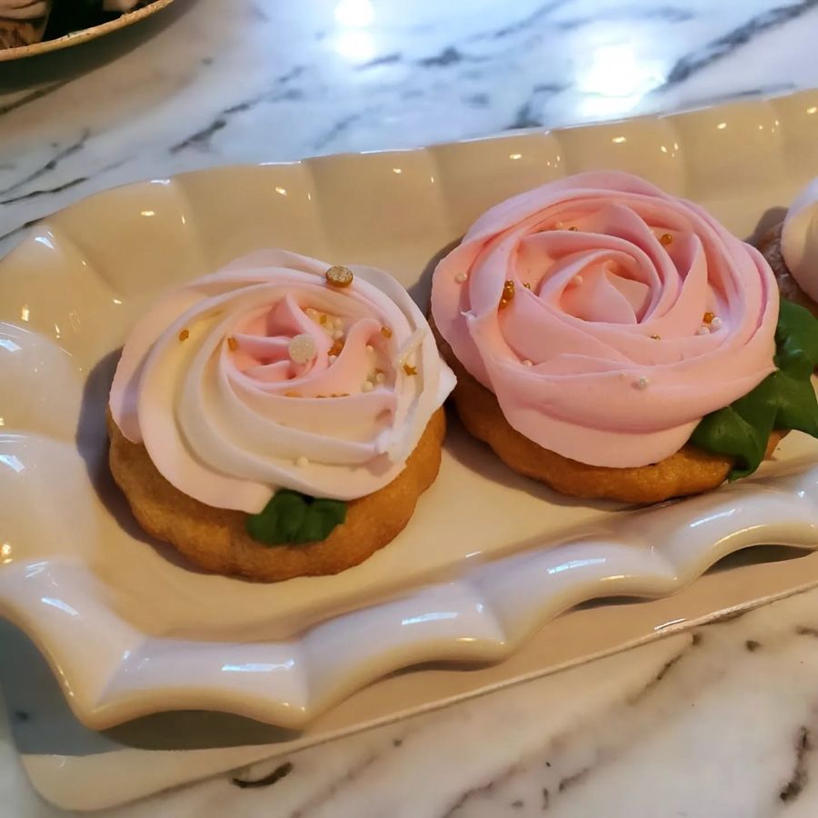 Sugar cookies topped with pink buttercream roses and gold sprinkles