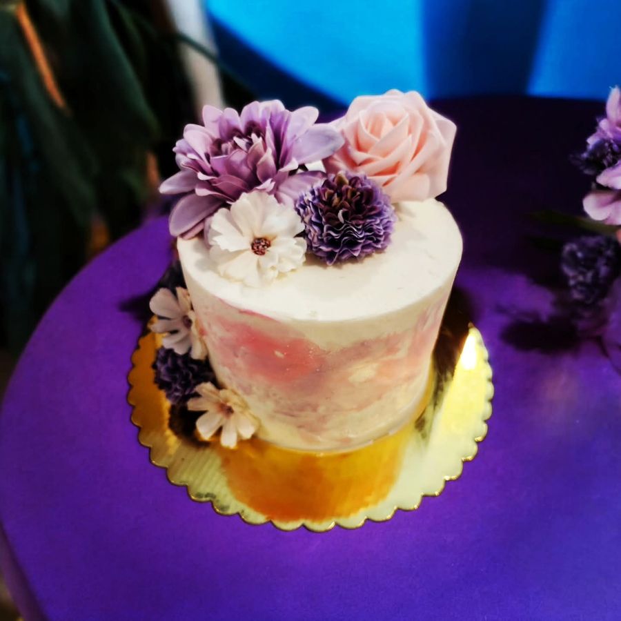 Watercolor buttercream cake topped with purple and pink flowers